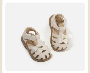 Detailansicht cremefarbener Baby-Sandalen für Mädchen mit zarten Schleifen und Perlen