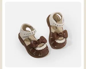 Close-up of brown and beige baby girl sandals with large bow and star details for summer.