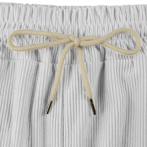 Close-up of white corduroy shorts waistband with beige drawstring bow and metal tips.