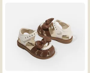 Elegant detail of brown toddler girl sandals featuring a large bow and star patterns