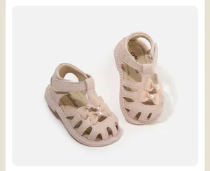 Nahaufnahme der rosa Kleinkindersandalen mit dekorativen Schmetterlingsschleifen und Perlen