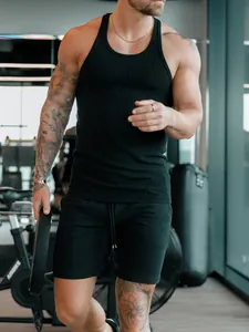 Détail d'un débardeur de fitness noir côtelé pour homme porté dans une salle de sport
