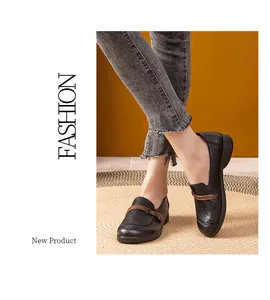 Close-up of black perforated leather loafers for women with brown decorative strap