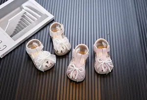 Elegant baby girl princess sandals with pearl bow decoration and soft sole detail.