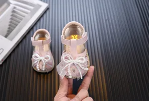 Detailed view of pink baby girl sandals with an elegant pearl bow and breathable soft sole.