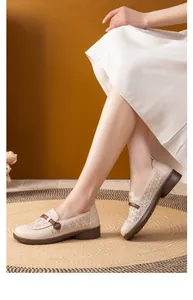 Close-up of beige leather loafers with floral laser-cut patterns and soft soles