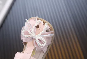 Macro view of pink princess sandal with delicate pearl bow and glitter ribbon detail