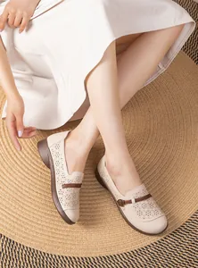 Detail shot of breathable beige hollow loafers for elderly women on a rug.