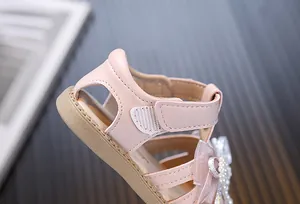 Macro detail of pink toddler princess sandals featuring pearl bow and soft Velcro strap
