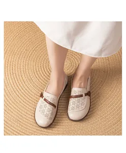 Top-down detail view of breathable beige perforated loafers for elderly women on a rug