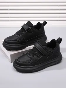 Détail de baskets décontractées en cuir noir pour enfants avec velcro et lacets