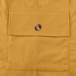 Detailed macro view of mustard yellow corduroy fabric texture and pocket button feature