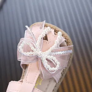 Close-up of elegant pink princess baby sandals featuring a shimmering pearl bow decoration