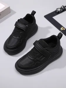 Vue détaillée de baskets en cuir noir pour enfants avec semelles épaisses et bandes velcro.