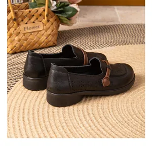 Detailed view of black perforated leather loafers for elderly women with brown strap