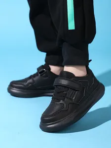 Détails visuels de baskets en cuir noir à semelle épaisse pour garçons portées en mode