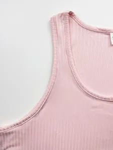 Gros plan sur la texture en maille côtelée rose et le décolleté d'un débardeur de sport homme