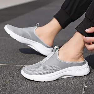 Side view detail of grey breathable mesh slip-on mule sneakers worn on stone pavement