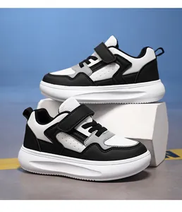 Vue de côté des baskets en cuir noir et blanc pour garçons avec une bande velcro