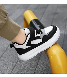 Vue latérale de baskets en cuir noir et blanc pour garçons avec semelles blanches épaisses.