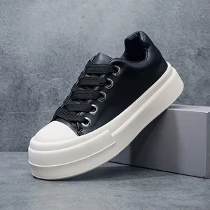 Close-up detail of stylish black leather platform sneakers featuring thick white soles and laces.
