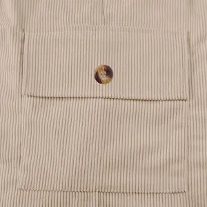 Close-up of beige corduroy fabric featuring a pocket flap and decorative button detail.