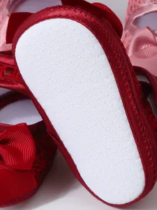 Detaillierte Nahaufnahme der weißen rutschfesten Sohle an roten Baby-Satin-Schuhen