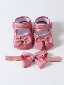 Detail der rosa weichen Babyschuhe mit eleganter Schleife und passendem Stirnband-Set