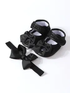 Detailansicht von schwarzen Spitzen-Babyschuhen mit passendem Schleifen-Stirnband