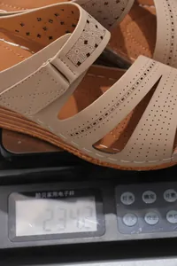 Gros plan d'une sandale compensée beige légère avec motif floral sur une balance