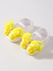 Primer plano de zapatos de princesa para bebé blancos con mariposa de lentejuelas.