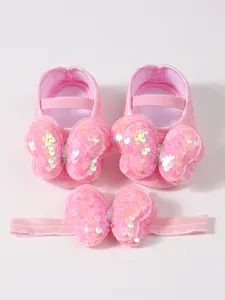 Primer plano de zapatos de princesa rosa para bebé con lazo de lentejuelas y diadema