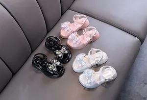 Detailed view of girls' princess sandals with sparkly bow and sequins in pink, black, and white