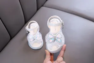 Detailed view of girls white princess sandals featuring a sequin bow and shiny rhinestones