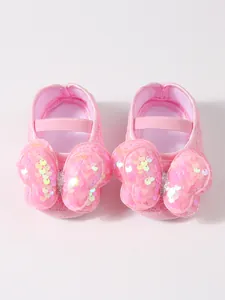 Detalle de zapatos de princesa para bebé de encaje rosa con un lazo de lentejuelas