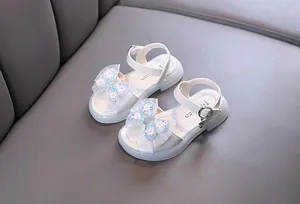 Detailed view of white girls princess sandals with sequined butterfly bow decoration.