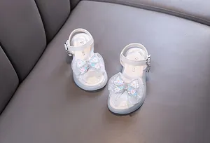Detailed view of white girls princess sandals featuring a sparkly bow and buckle strap