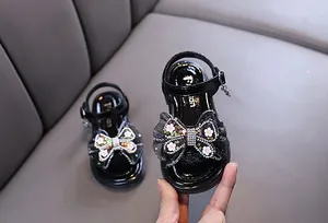 Close-up of girl's black princess sandals with rhinestone butterfly bow detail