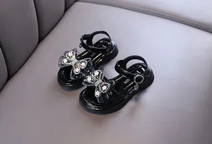 Detail showing the rhinestone bow and flower accents on black girls' princess sandals.