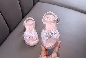 Pink princess sandals for girls with rhinestone butterfly bow and heart charm details.