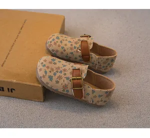 Detailed view of children's floral pattern clogs with brown leather buckle straps
