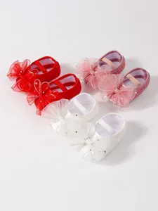 Nahaufnahme von roten rosa und weißen Baby Prinzessin Schuhen mit eleganten Netzschleifen