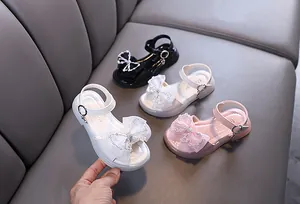 Detailansicht der glitzernden Sandalen mit Strassschleife in Weiß, Rosa, Schwarz und Beige
