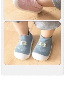 Nahaufnahme atmungsaktiver Baby-Strickschuhe mit gelbem 'B' und rutschfester Weichsohle