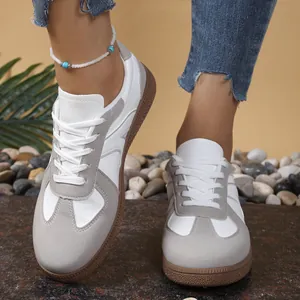 Retro German army trainers in white soft leather with grey suede details on feet.