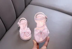 Detaillierte Nahaufnahme von rosa Prinzessinnen-Sandalen mit glitzernder Strassschleife.