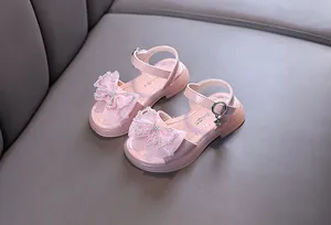 Nahaufnahme der zarten Spitzenschleife mit Strass-Akzenten auf diesen rosa Sandalen.