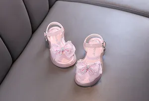 Nahaufnahme von rosa Mädchen Prinzessin Sandalen mit einer glitzernden Schmetterlingsschleife