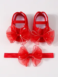 Nahaufnahme von roten Baby-Prinzessin-Schuhen und Stirnband mit Tüllschleifen