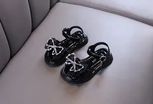 Nahaufnahme schwarzer Prinzessinnen-Sandalen für Mädchen mit eleganter Strass-Schleife